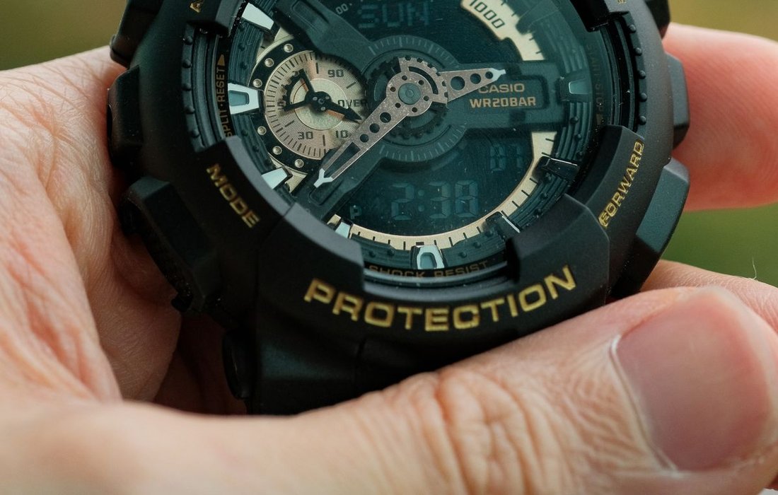 Rugged shock resistant digital watch held in hand outdoors