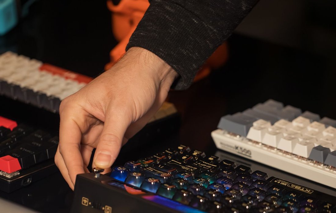 Person adjusting a mechanical gaming keyboard on a desk
